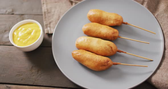 Video of corn dogs with dips on a wooden surface