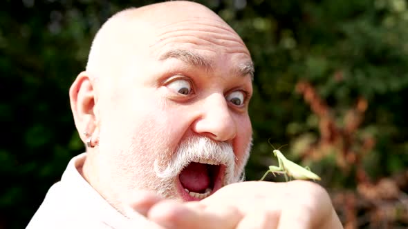 Surprised Openeyed Old Man Look at Insect on Hand Sticking Tongue Out Mantis