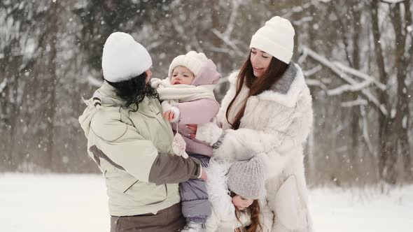 Mother with Kids Standing in Winter Forest on Snowy Weather