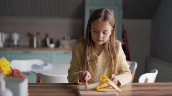 Concentrated girl cuts banana