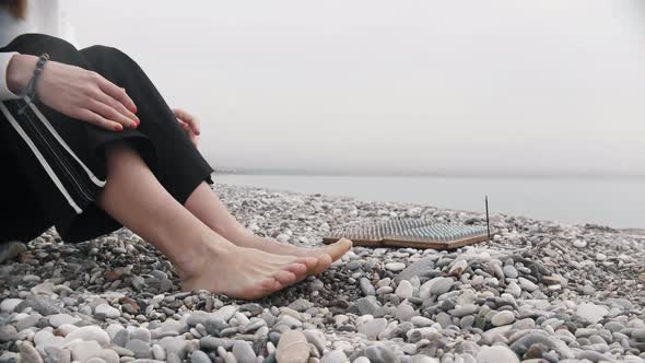 A Woman Sits Near the Sadhu Board on the Seashore