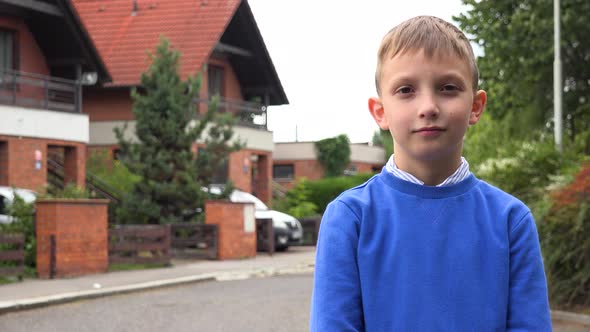 A Young Boy Shows a Thumb Up To the Camera in a Suburban Street