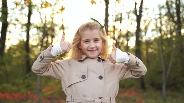 Happy Girl Gesturing Thumbs Up in Autumn Forest