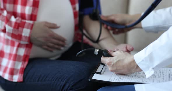 Doctor Measures Blood Pressure of Pregnant Woman Closeup