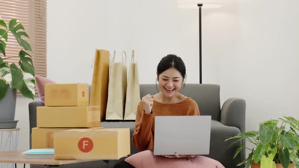 Happy young Asian woman enjoy to shopping from online shopping platform by laptop computer.