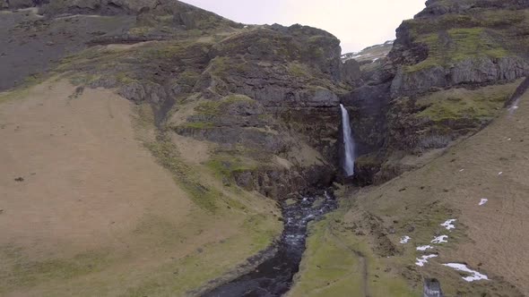 Aerial view of waterfall in Iceland with snowy mountains on background