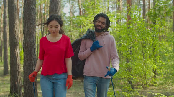 Multiracial Volunteer Couple Picking Up Litter in Forest