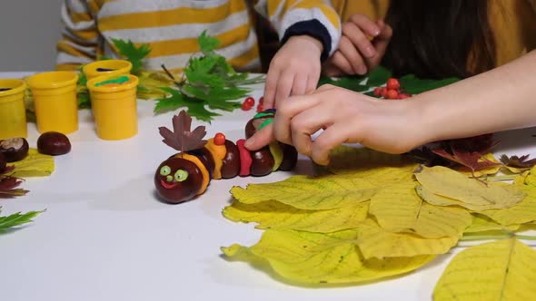Mother and Son Decorate the Autumn Craft Chestnut Caterpillar with Viburnum