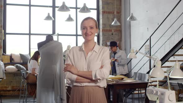 Female Dressmaker Smiling and Posing for Camera in Sewing Workshop