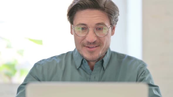 Portrait of Middle Aged Man Talking on Video Call on Laptop