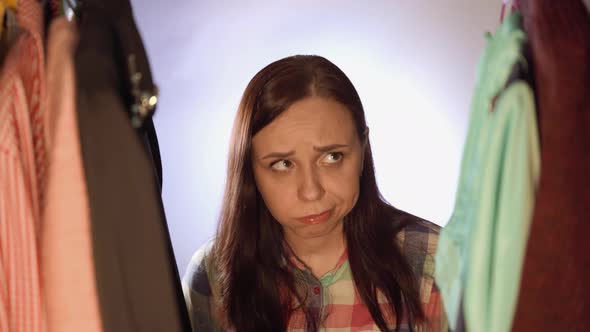 Close Up of Young Woman Standing Between Clothes and Choosing Things in Wardrobe