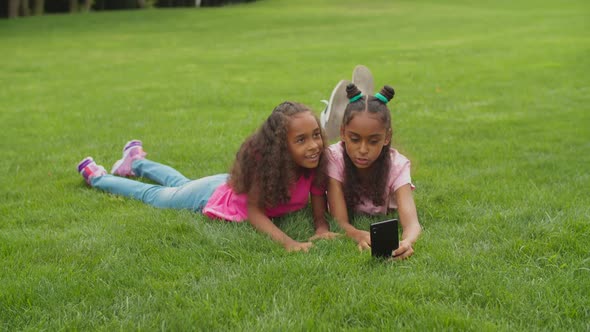 Sisters Video Conferencing Online Lying on Grass