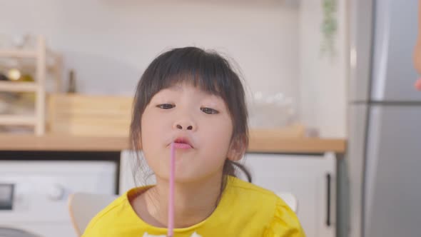 Asian young girl blow air to the candles on Birthday cake having traditional celebration party.