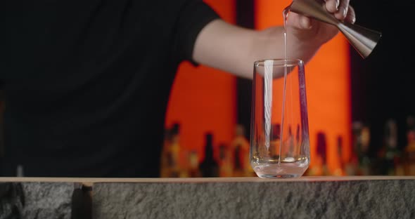 Bartender Pours Portion of Alcohol From Jigger to the Cocktail Glass in Slow Motion Making the