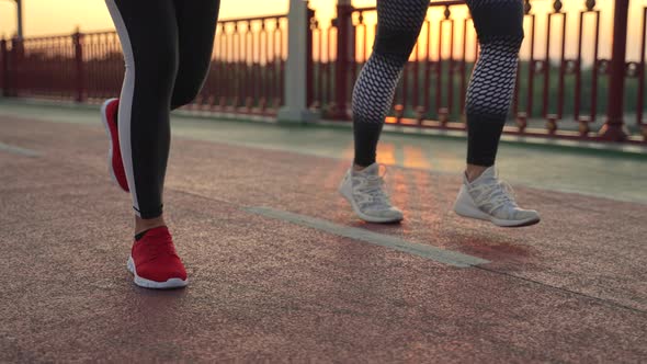 Legs of Sporty Women Jogging on Bridge at Sunset