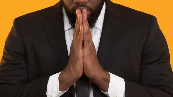 Superstitious Black Male Praying Before Important Deal, Hoping for Success