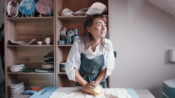 a Woman Potter Wearing an Apron Preparing and Rolling Clay