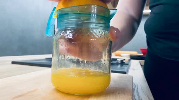 Juicing fresh orange for healthy juice on kitchen counter from side shot in slow motion