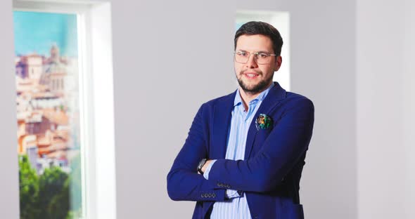 Portrait of Handsome Young Caucasian Male Real Estate Agent in Suit Standing in Empty Apartment