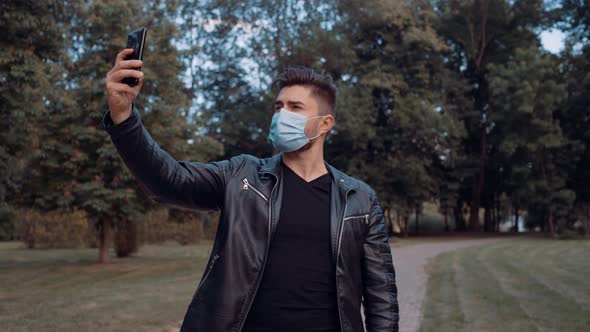 A Young Man Dressed in Black Clothes Takes a Selfie with His Mobile Phone,