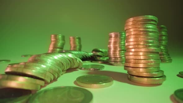 Stacks of Coins Fall Down on Table at Gentle Green Light