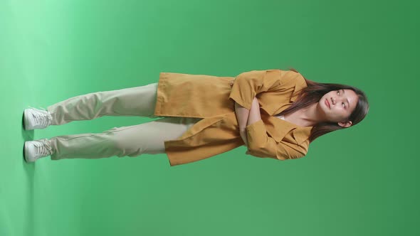 Full Body Of Asian Woman Emotionally Flipping Something While Standing In The Green Screen Studio