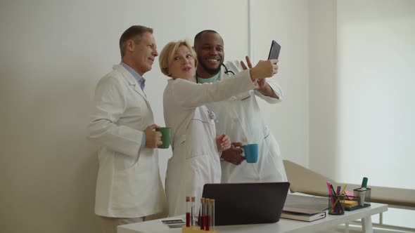 Cheerful Diverse Multiethnic Healthcare Workers in Lab Coat Posing for Selfie Shot at Medical Office