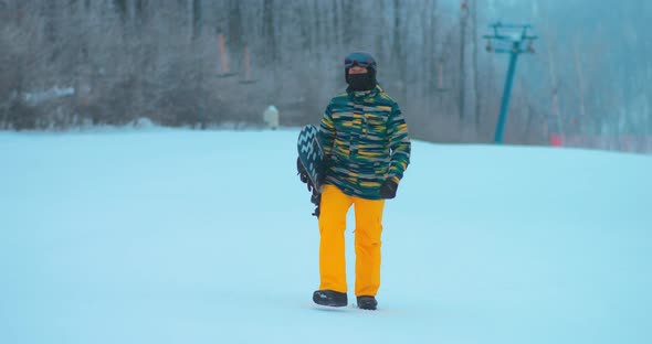 Professional Snowboarder Climbs with a Snowboard for a Descent