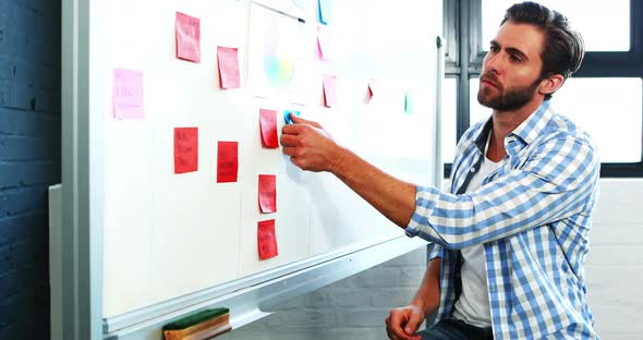 Man putting sticky notes on whiteboard