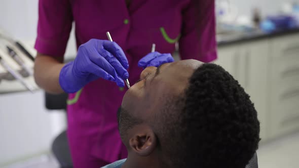 Young AfricanAmerican Black Male Patient Opening Mouth While Female African Dentist in Blue Latex