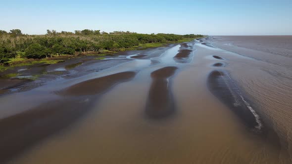 Aerial shot of waves, sand banks and green nature by Rio de la Plata