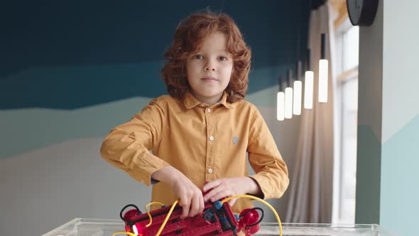 Portrait of Red-haired Boy Putting Robo Boat in Water