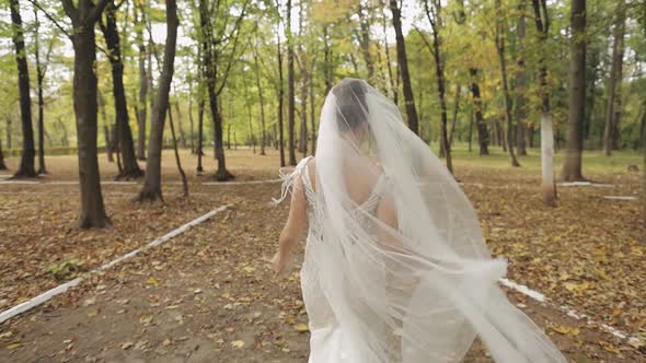 Beautiful and Lovely Bride in Wedding Dress Running in the Park. Slow Motion