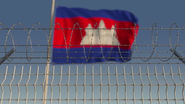 Waving Flag of Cambodia Behind Barbed Wire Fence