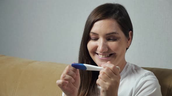 Closeup of Young Woman Happily Looking at Pregnancy Test