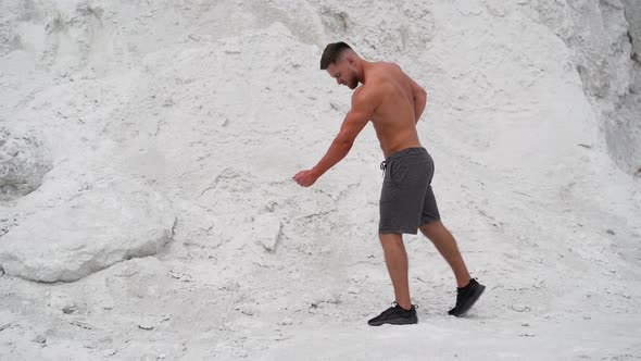 Strong athlete posing to camera with his muscular body outdoors