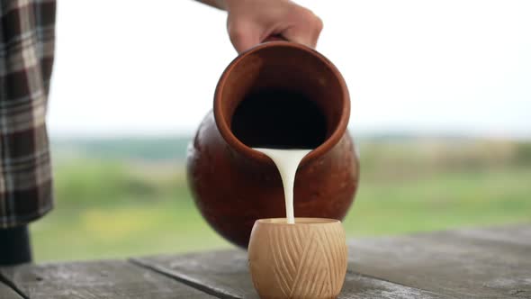 Closeup Pouring White Healthful Vitamin Milk in Slow Motion Outdoors