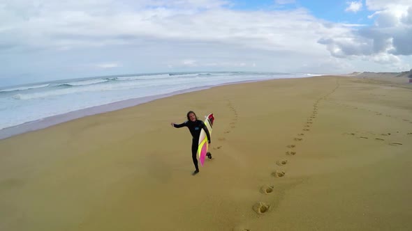 Aerial view of a surfer running on the beach before surfing