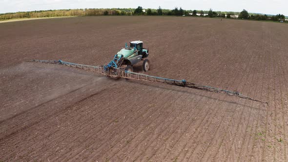 Tractor spraying field with fertilizer