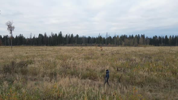 Woman in a Blue Jacket Walks Through an Autumn Field