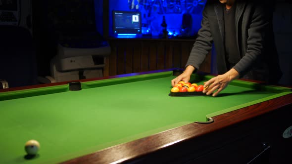 Man racking up pool balls on a pool table in a pub bar