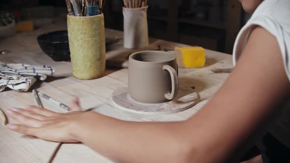 Young Woman Potter Rolling Out a Small Piece of Clay