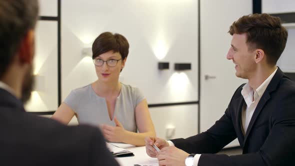 Smiling Business Partners Having Discussion at Meeting Table