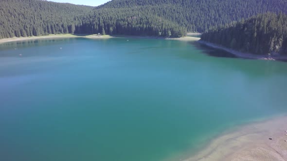 Drone footage over clean, green, lake water. Sunny, bright day.