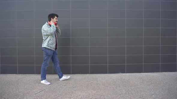 man puts on red headphones and walks while looking at red cell phone