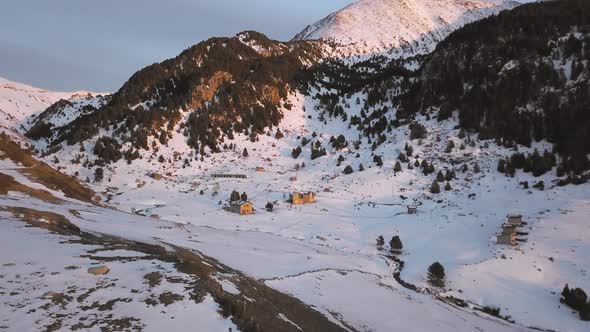 Smooth drone traveling through the snowy town of Cortals in Andorra, with the last lights of the day