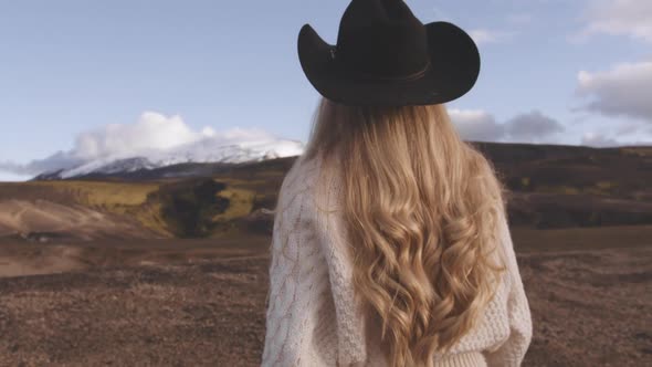 Blond Woman In Cowboy Hat Walking In Icelandic Landscape