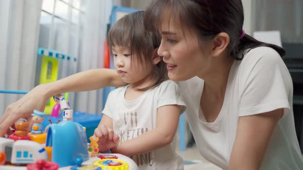 Asian happy family, beautiful mother and little girl kid playing toy together in living room at home