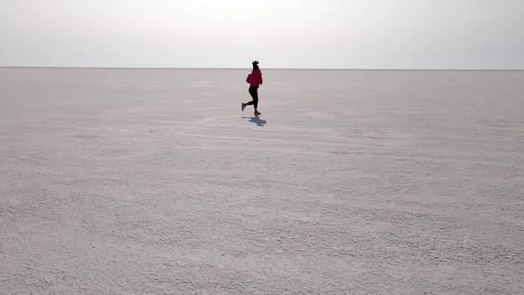 Aerial shot of an Asian woman jogging across the Bonneville Salt Flats flats