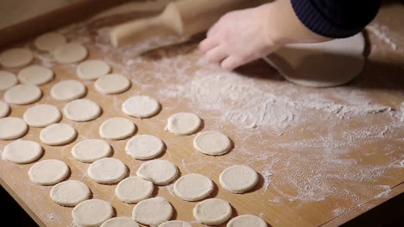 Woman molds dough at home. Roll out the dough with a rolling pin